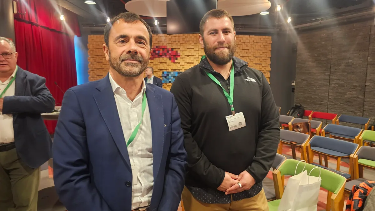 Dos asistentes posan en la sala, con las sillas del auditorio al fondo.