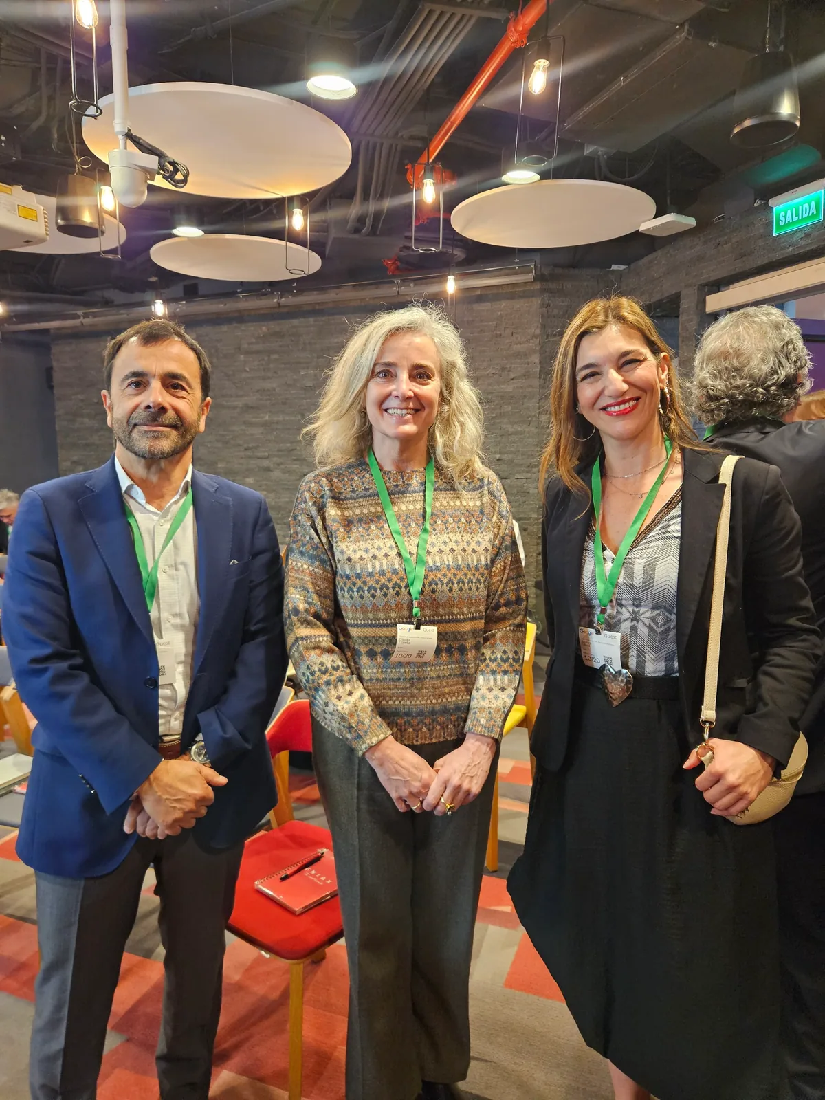 Tres asistentes posan juntos en la sala durante el networking.